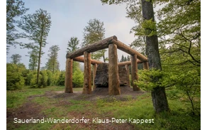 Die Holzstämme umringen den Stein der Stein-Zeit-Mensch Skulptur