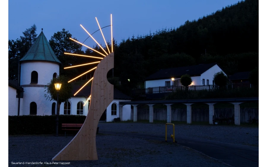 Museum von außen bei Nacht mit einer künstlerisch beleuchteten Holzfigur im Vordergrund