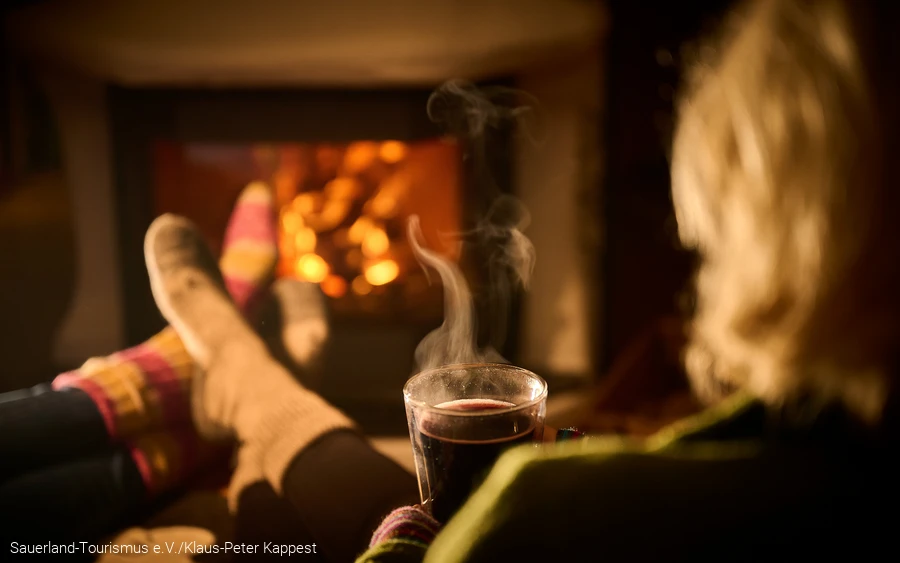 Frau entspannt mit einem heißen Tee Eine Frau entspannt mit einem heißen Tee vor dem Kamin
