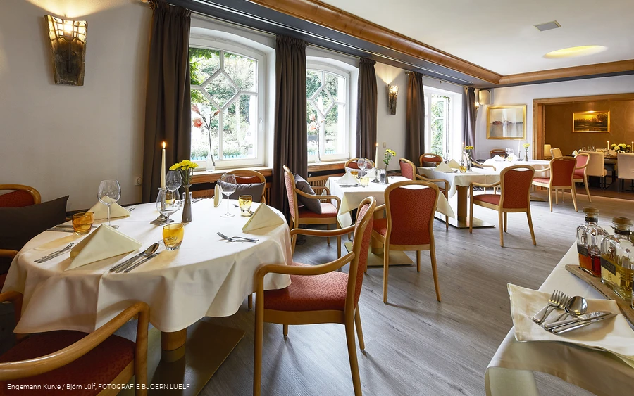 Einige eingedeckte Tische mit Stühlen in einem Restaurant.