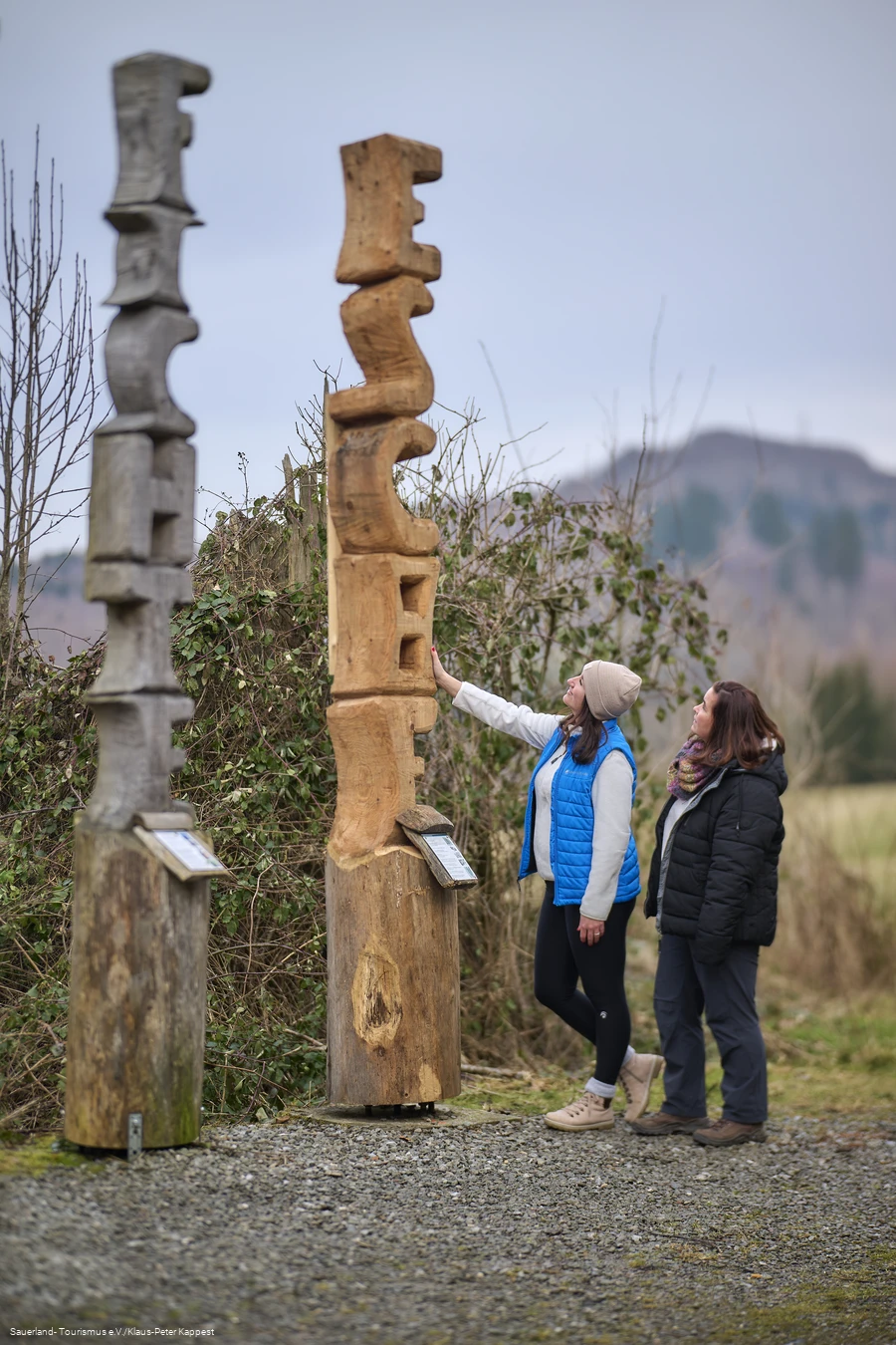 Zwei Wanderinnen an einem Baumkunstwerk